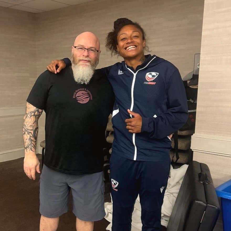 Chris of Muscle Movement & Improvement standing with a USA Rugby athlete beside his massage table