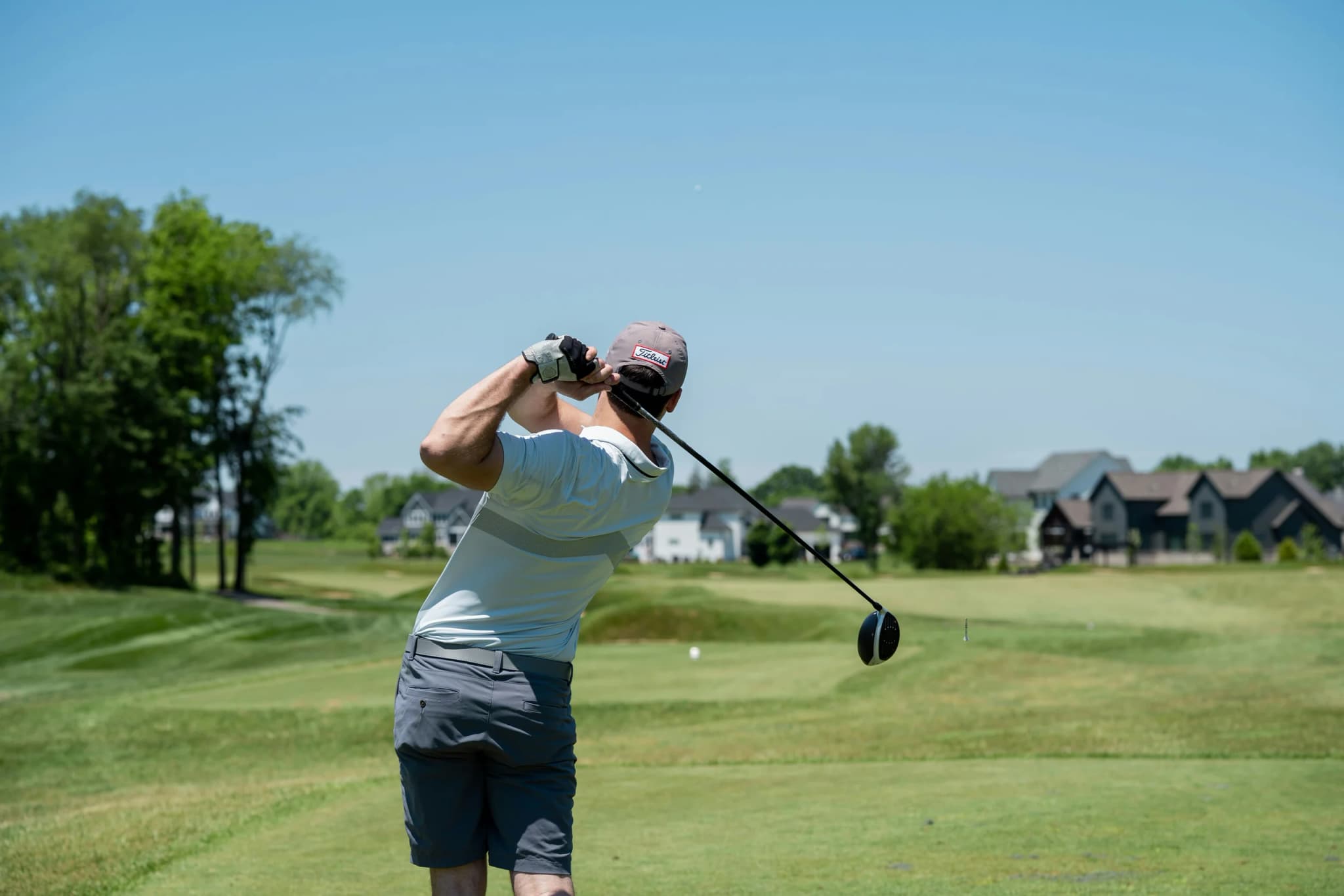 Golfer following through on a drive at a sunny golf course