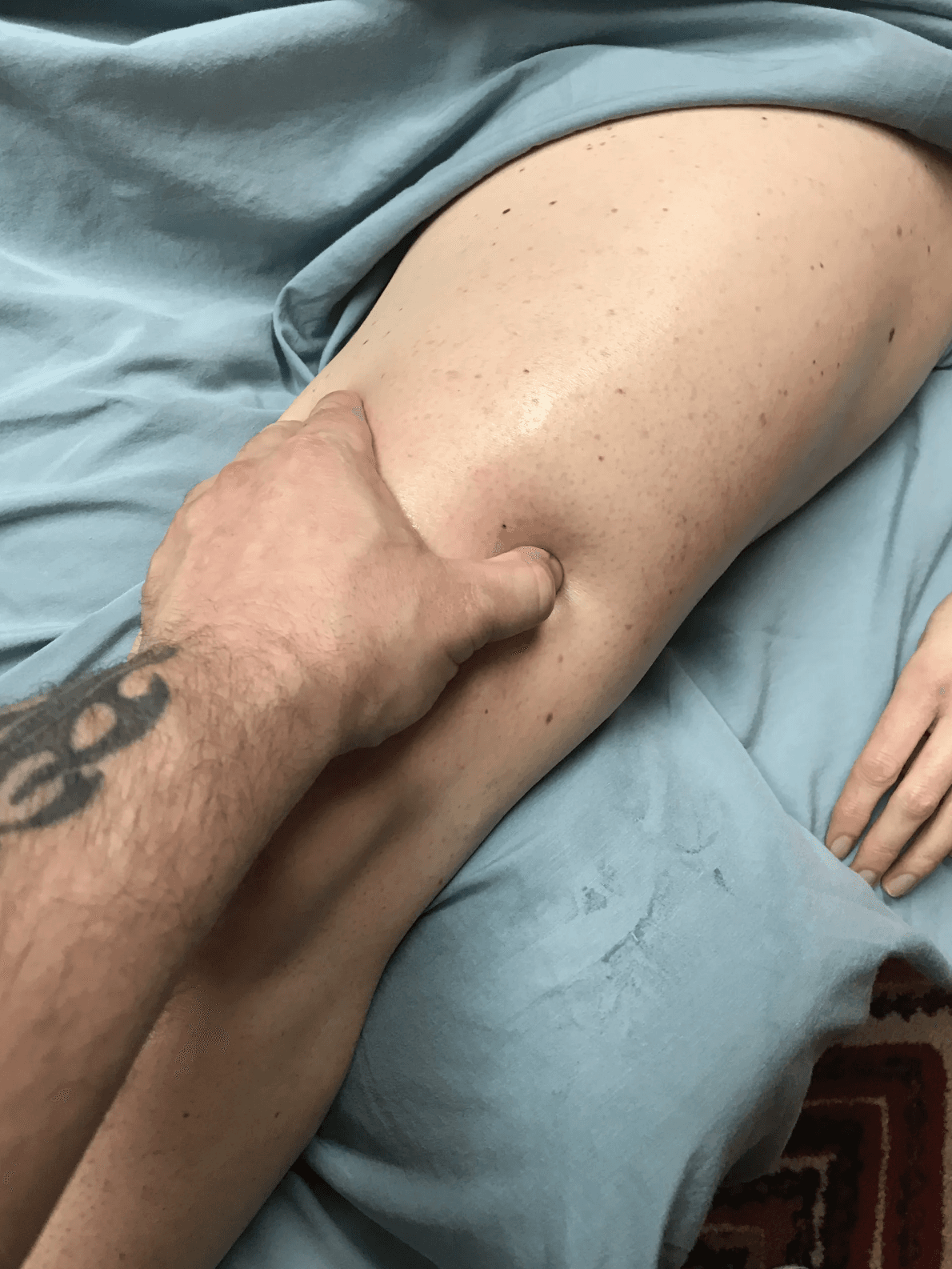 Focused thumb pressure on a client's leg during trigger point bodywork