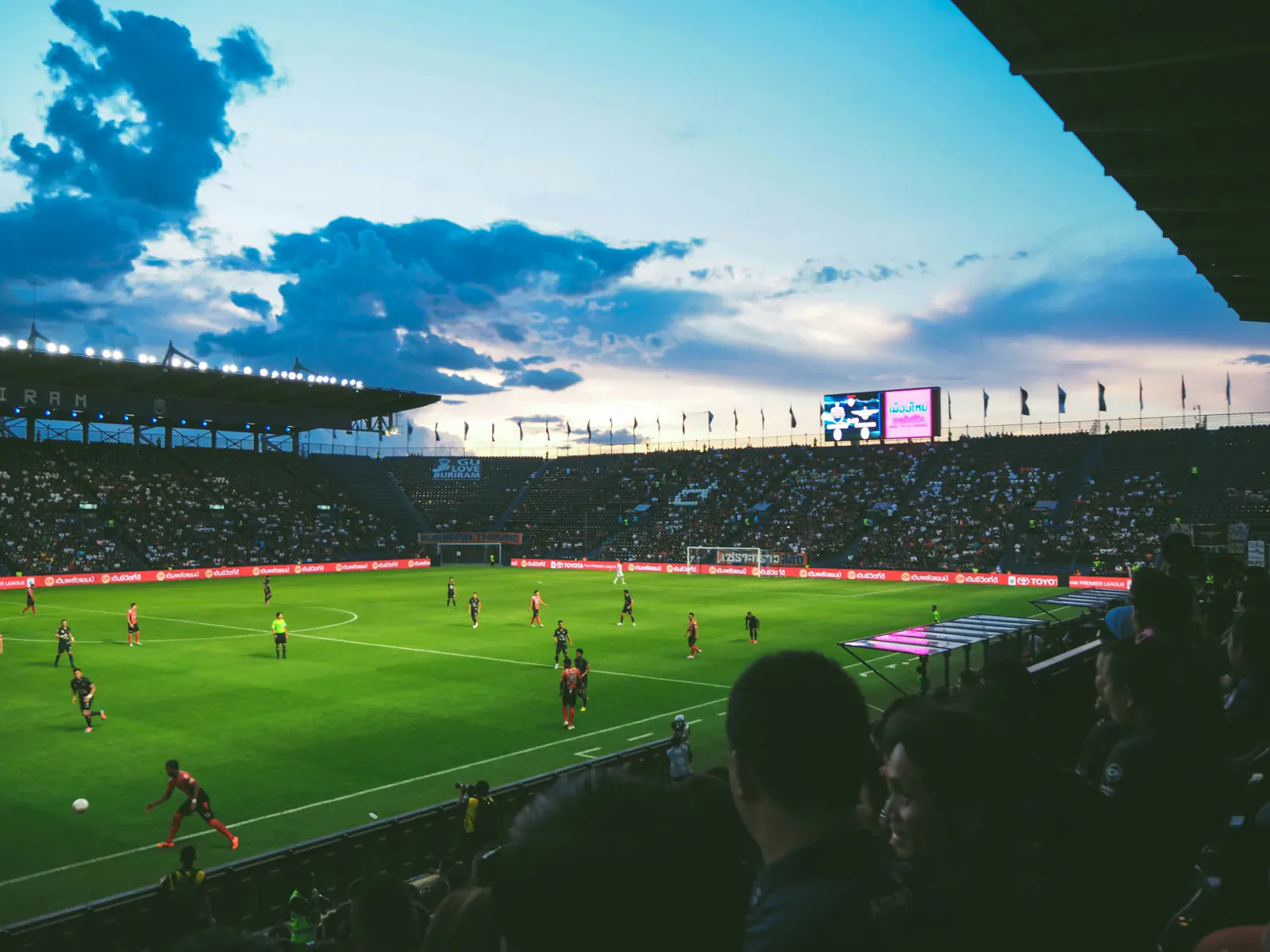 Soccer match under a dramatic evening sky in a packed stadium