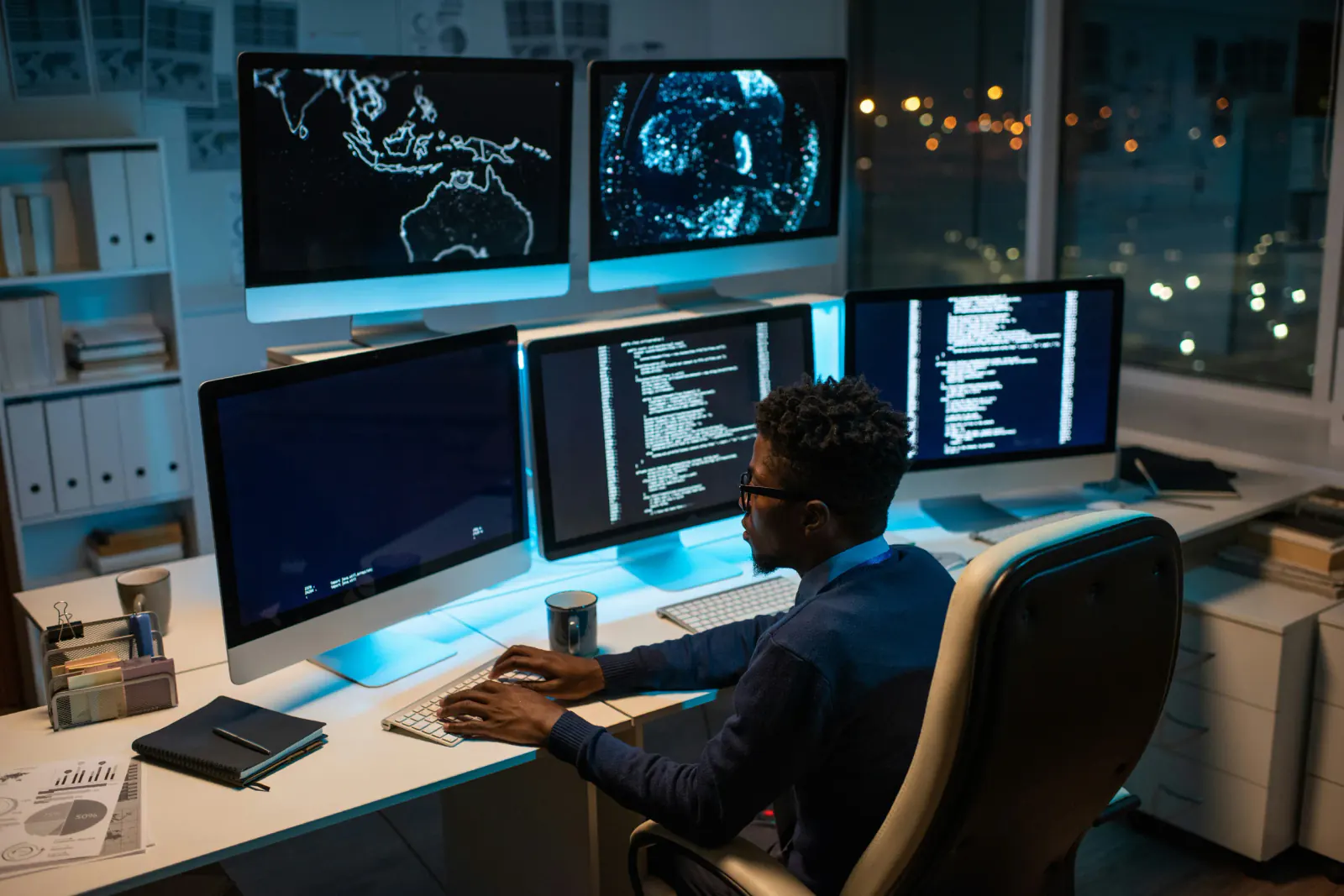 Professional working at a desk surrounded by multiple computer monitors