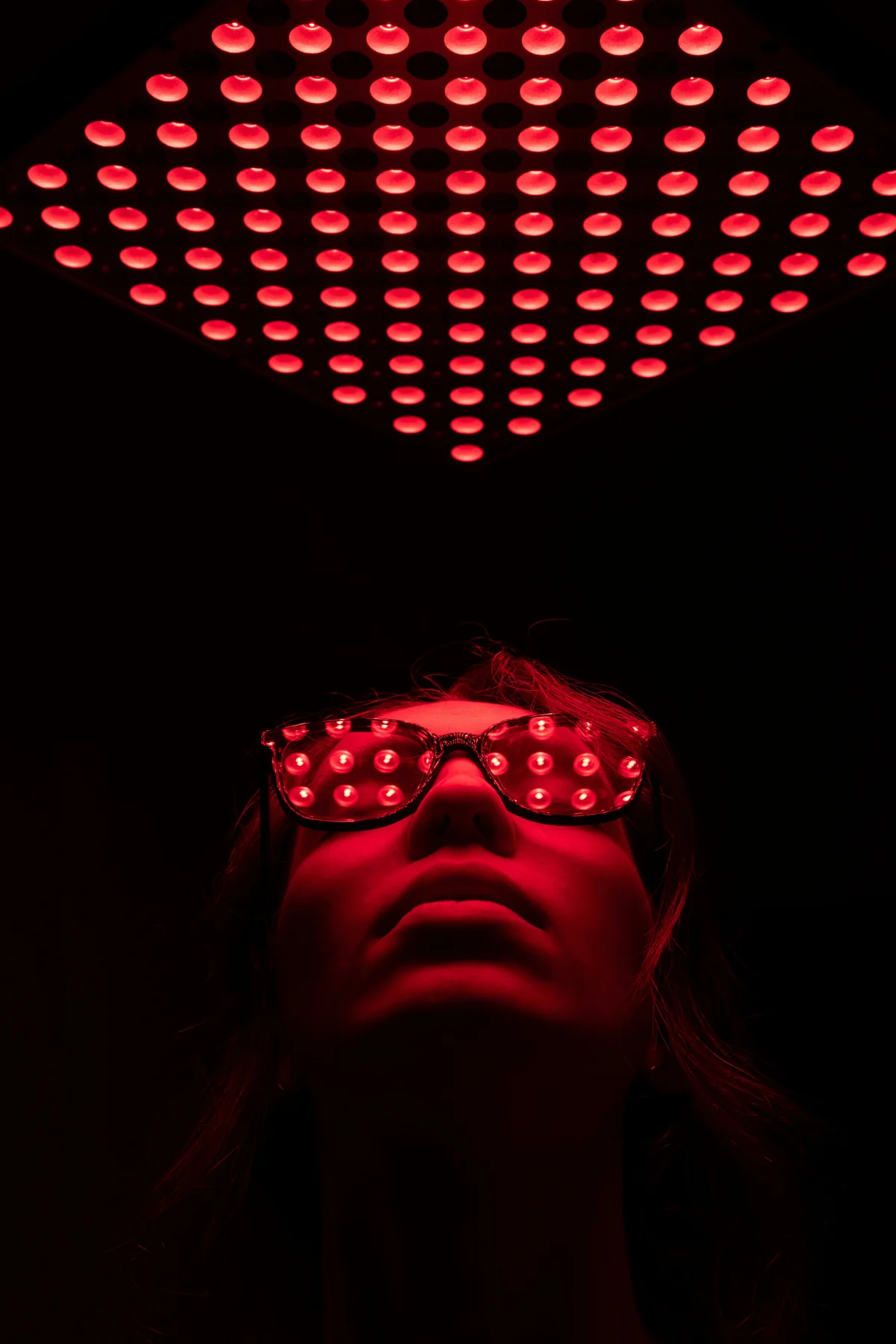 Client receiving infrared red-light therapy while wearing protective glasses