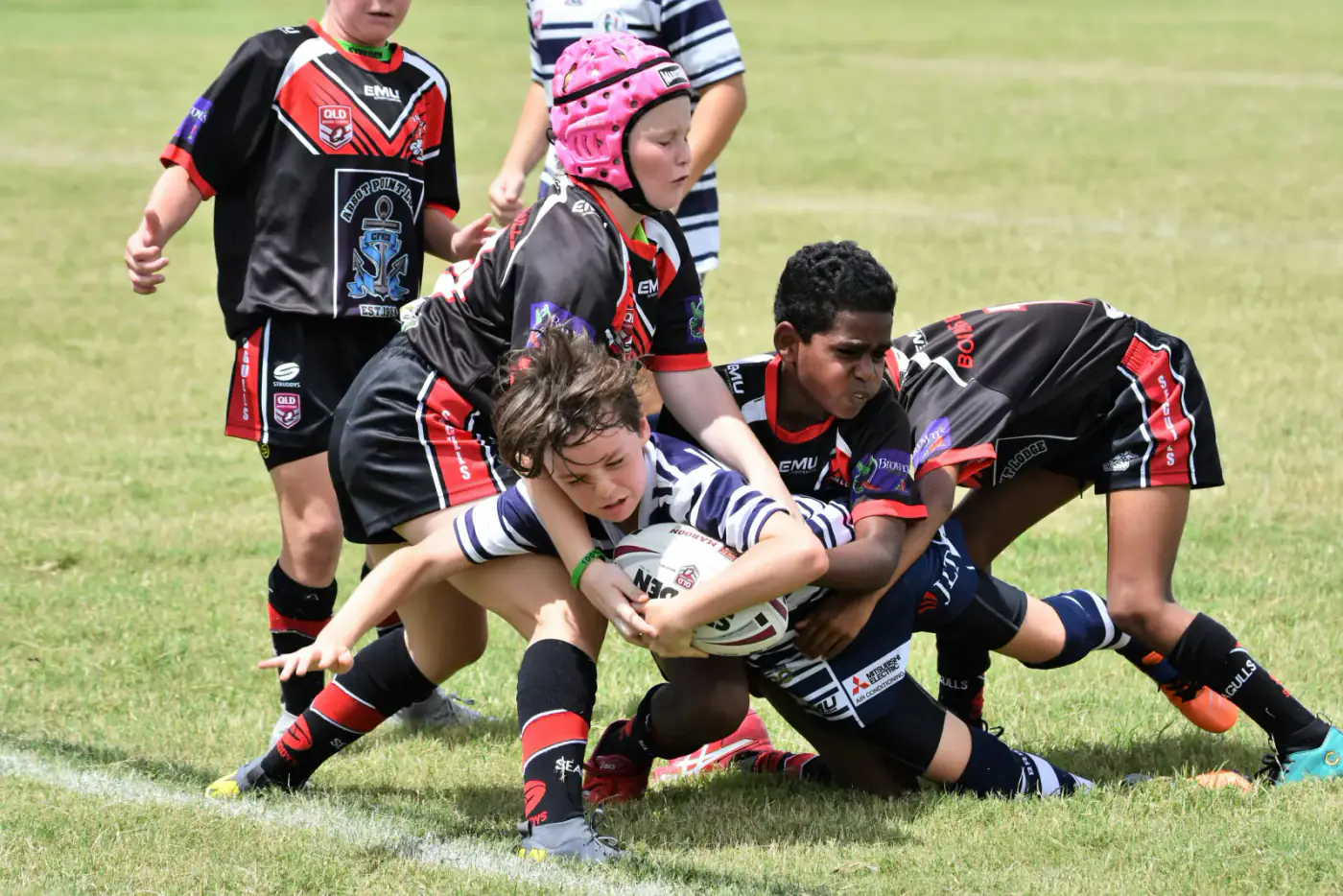 Youth rugby players competing for the ball on a grass field